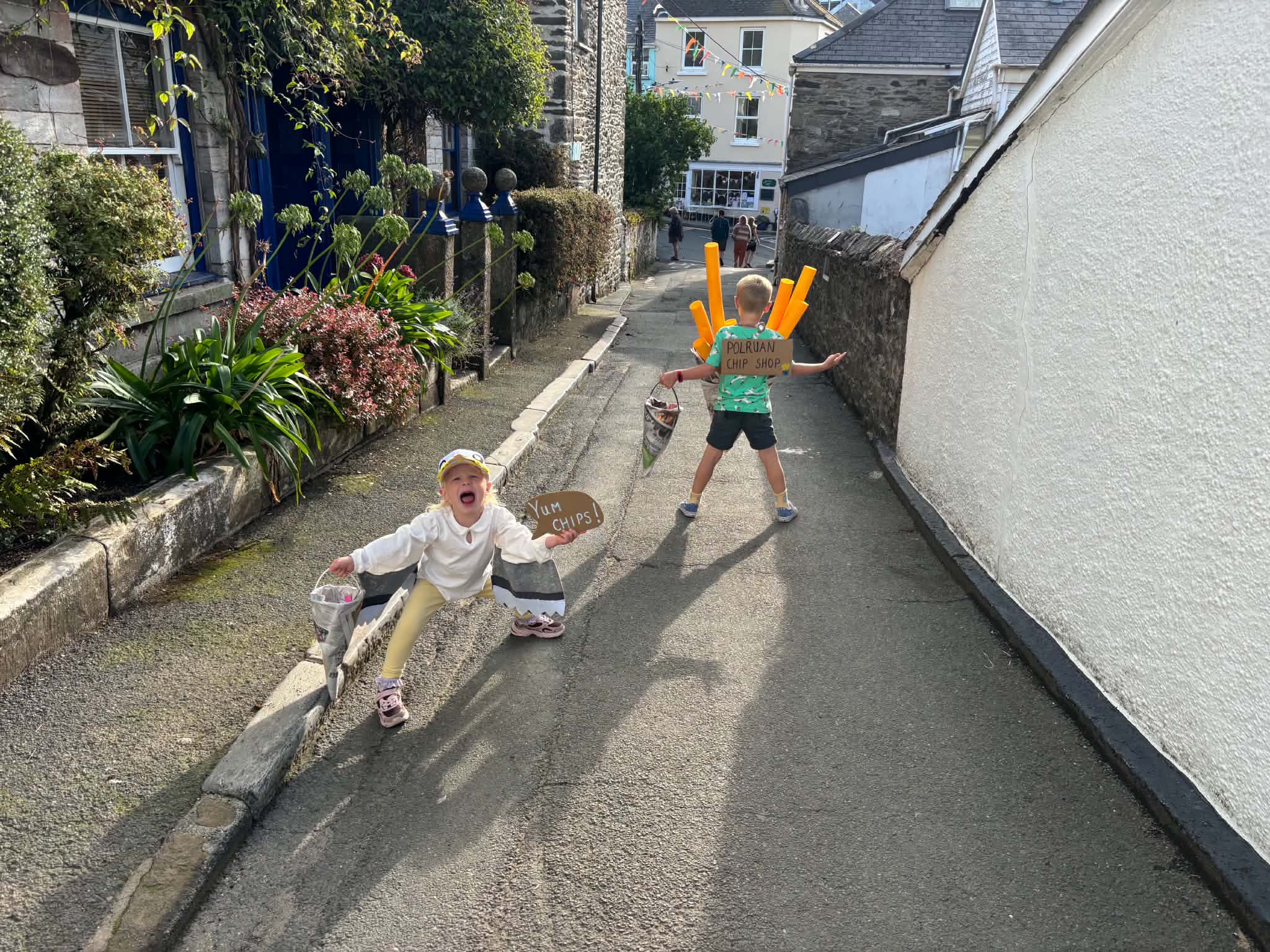 Children posing in seagull and chip-shop fancy dress on a sunny Polruan street