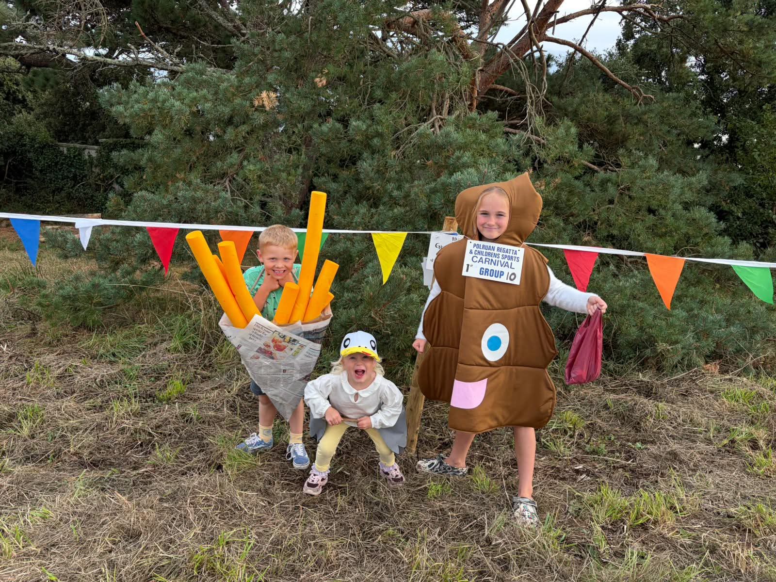 Three young carnival entrants in chip-shop themed costumes with a first-prize sign